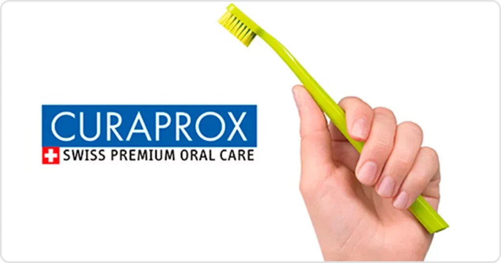 Hand holding a green Curaprox toothbrush, ideal for premium oral care at Hola Sonríe, dental office in Coyoacán, CDMX.