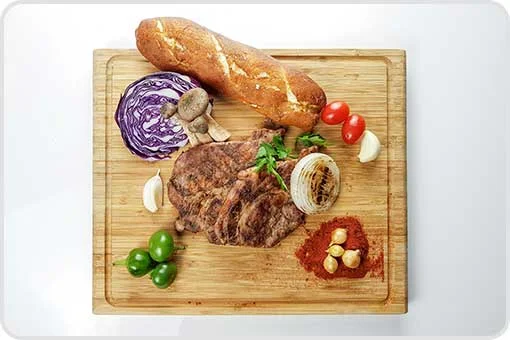 Tabla de madera con carne asada, pan crujiente y vegetales duros, alimentos no recomendados tras una extracción dental en Coyoacán, CDMX